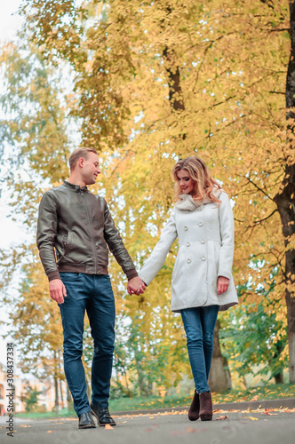 loving couple tenderly holding hands against the backdrop of an autumn park, the concept of romantic relationships and first love