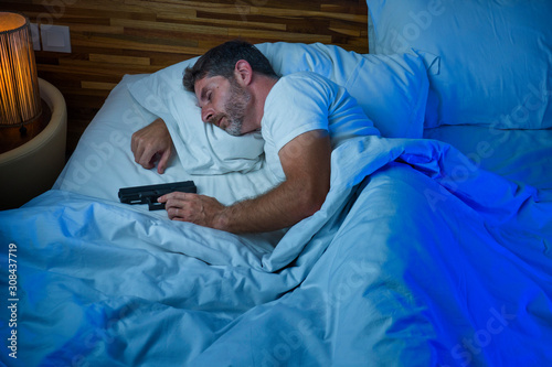 Tableau sur toile night portrait of young stressed and paranoid American man in bed sleeping and h