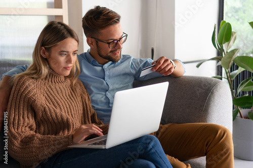 Young couple ordering online, looking in laptop