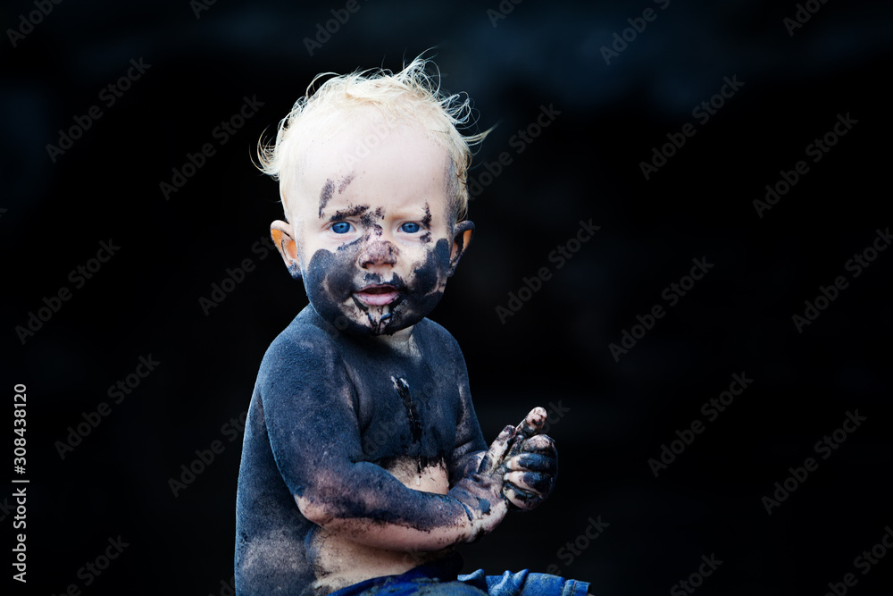 Funny portrait of happy smiling child with dirty face, hands playing with fun on black sand beach in sea water pool before swimming. Family lifestyle active leisure on summer vacation with little baby Funny portrait of happy smiling child with dirty face, hands playing with fun on black sand beach in sea water pool before swimming. Family lifestyle active leisure on summer vacation with little baby