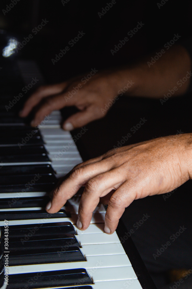 Obraz premium two male hands on the piano. palms lie on the keys and play the keyboard instrument in the music school. student learns to play. hands pianist. black dark background.