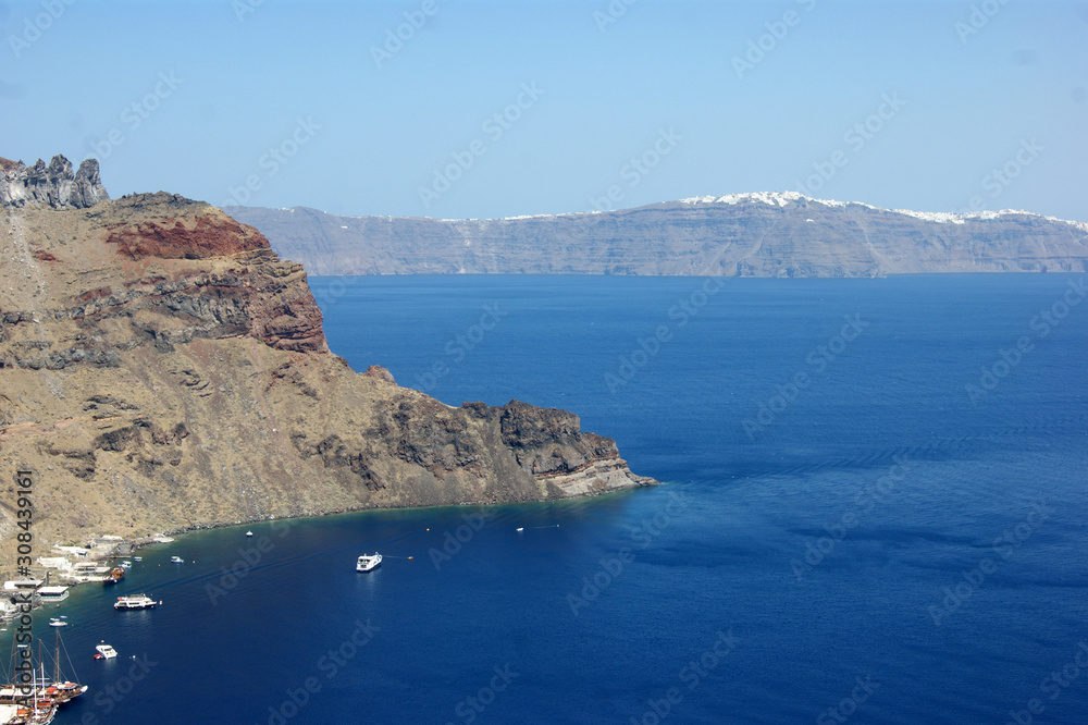 Greece, Thirasia island.  A lesser known hidden gem, quieter than the well know adjacent island of Santorini.  A view of the port on a summers day.  In the distance, at Santorini, is the town of Oia. 