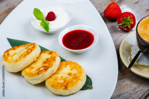 Traditional breakfast with coffee and cheesecakes  cottage cheese pancakes on a plate with syrup and jam.