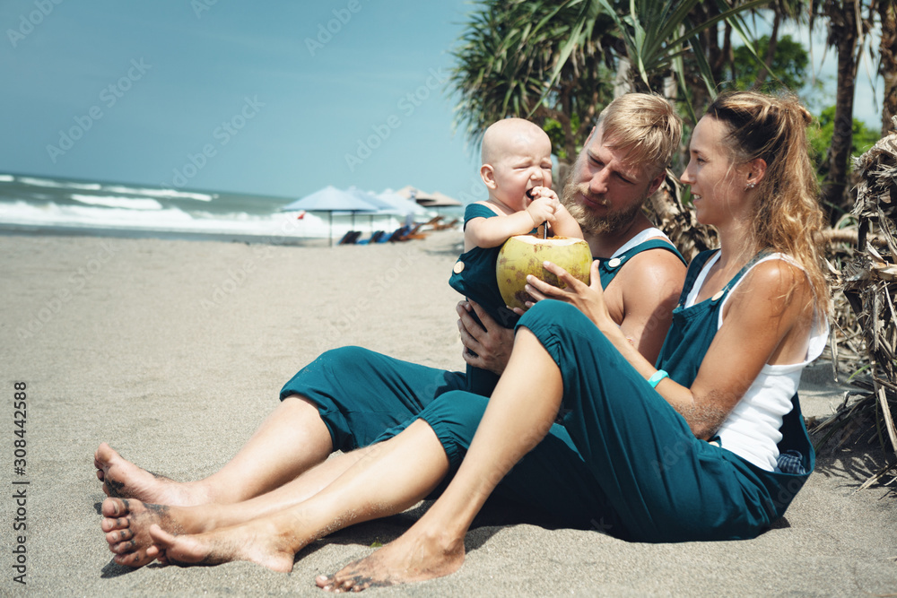 Happy family have funny picnic on beach - drink young coconut Happy family have funny picnic on beach - drink young coconut