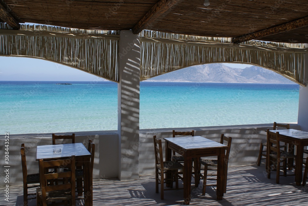 Koufonissi island, Greece. A taverna by the beach on a summers day. A shaded terrace with the deep blue of the Aegean sea in the background.