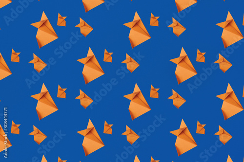Pattern of red different size origami foxes on the trendy blue background © Halyna