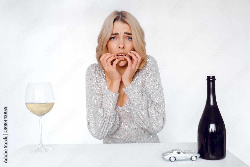 Glamorous girl on a white background with bottles of wine and a toy car. woman says stop drinking alcohol. concept of not drinking while driving. Glamorous girl on a white background with bottles of wine and a toy car. woman says stop drinking alcohol. concept of not drinking while driving.