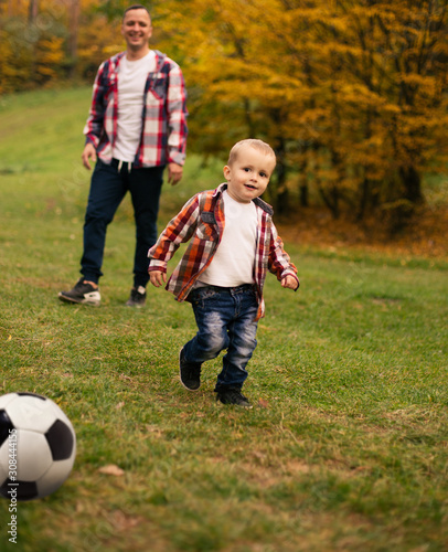 Son playing with ball on grass