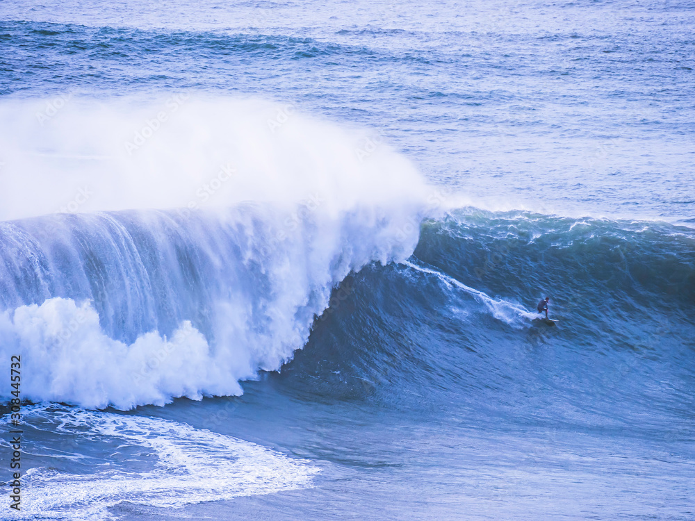 Surfer surfing massive waves at Nazare Portugal