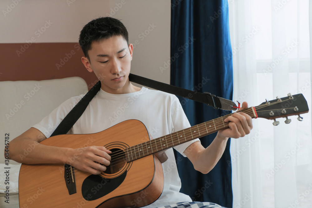 Obraz premium Asian man play guitar at home, feel relaxing