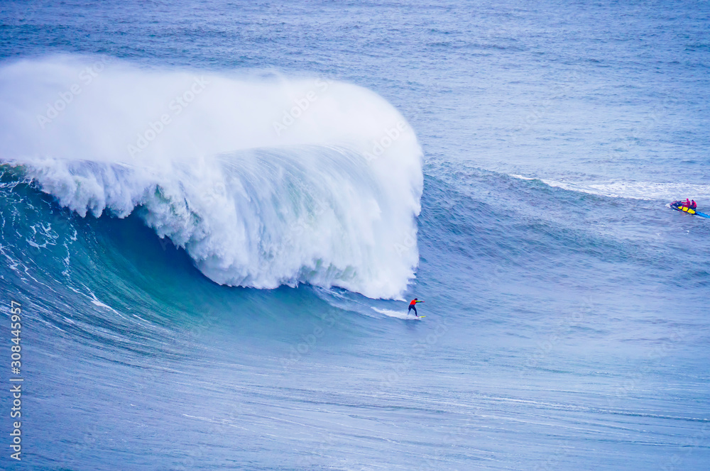 Surfer surfing massive waves at Nazare Portugal