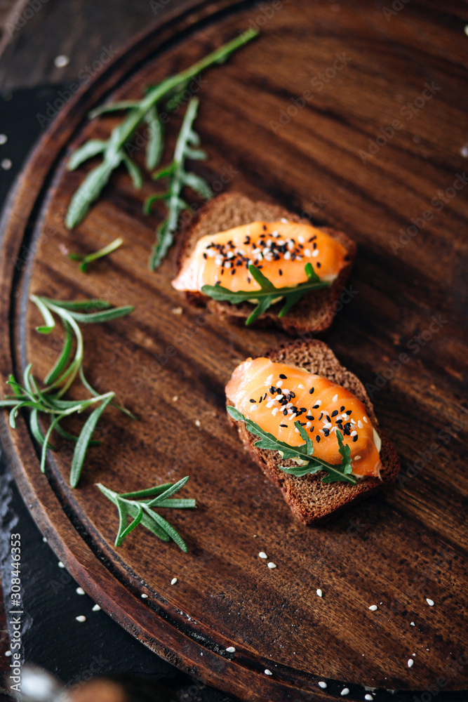 Red fish on rye bread with arugula and sesame. Fish rope. Restaurant appetizer with red fish Red fish on rye bread with arugula and sesame. Fish rope. Restaurant appetizer with red fish
