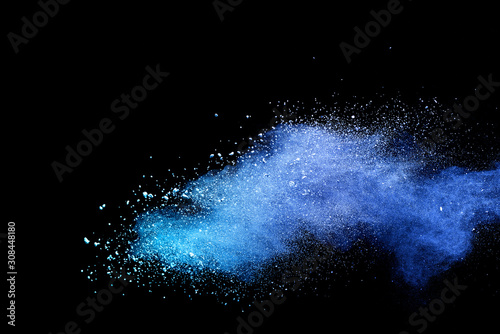 Abstract brown powder explosion. Closeup of blue dust particle splash isolated on black background.