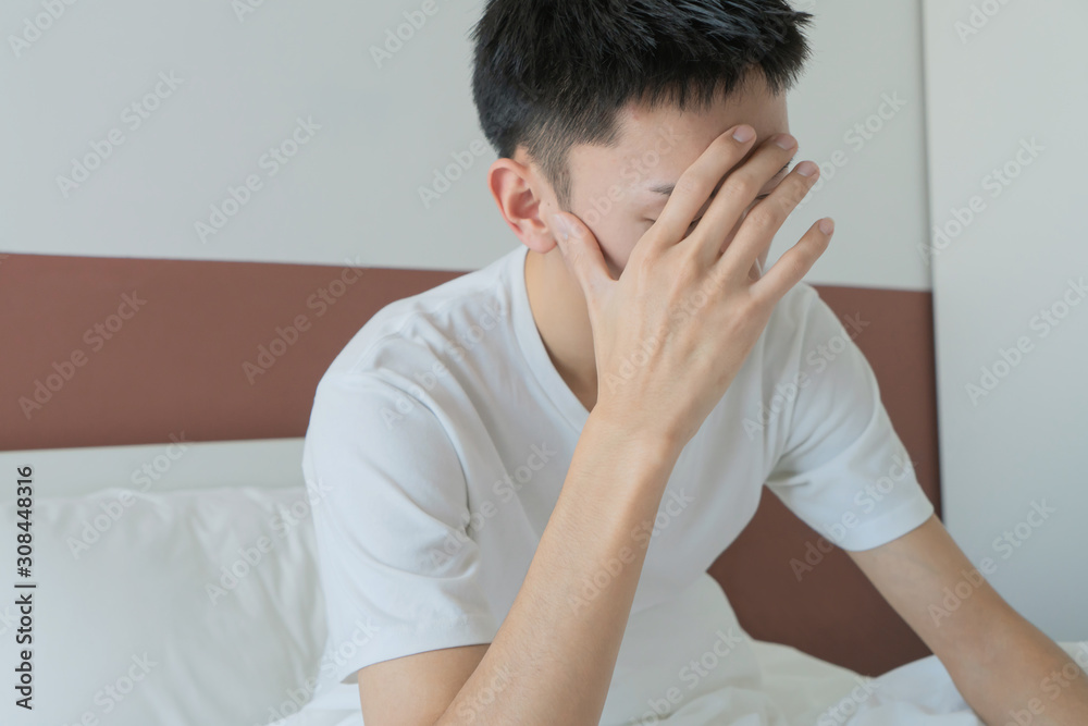 Asian Sad single man lamenting sitting on the bed of an hotel room or home Asian Sad single man lamenting sitting on the bed of an hotel room or home