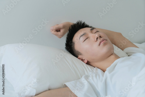 a young man waking up in bed and stretching his arms