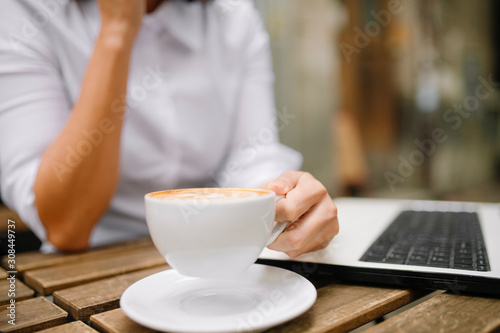 Close up of businesswoman holding cup of coffee and working outdoors. 