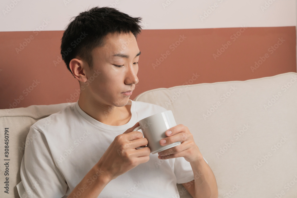 asian young man drink coffee sit in sofa asian young man drink coffee sit in sofa