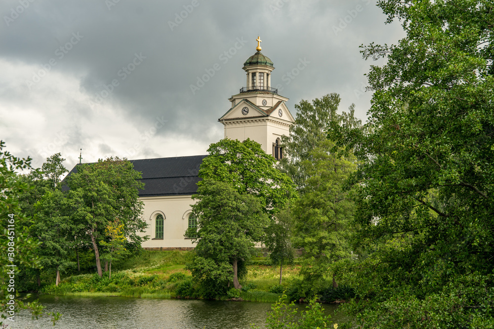 White stone church in bright sunlight and lush green environment