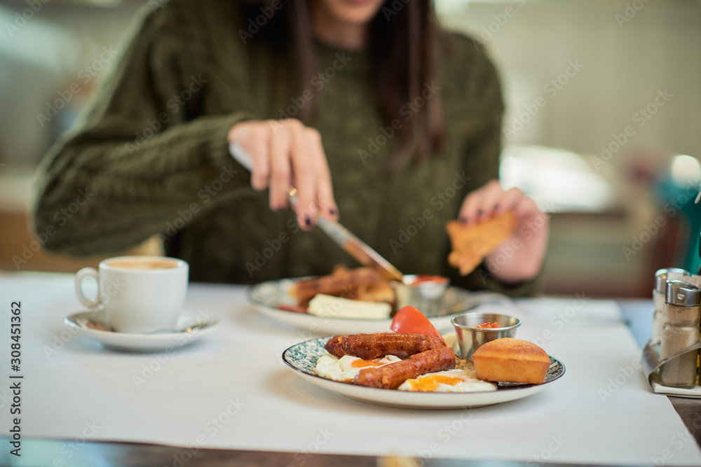 Close up of caucasian woman in sweater sitting in restaurant and having french toast for breakfast. Close up of caucasian woman in sweater sitting in restaurant and having french toast for breakfast.