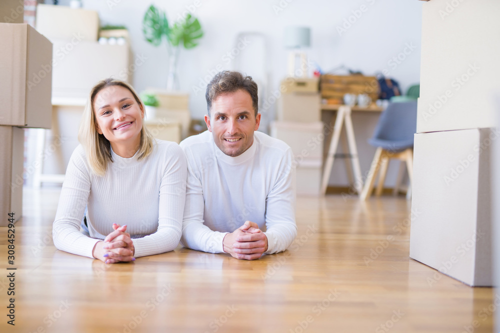 Young beautiful couple lying down on the floor at new home around cardboard boxes Young beautiful couple lying down on the floor at new home around cardboard boxes