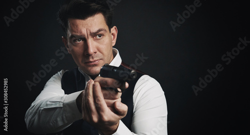 Serious man is holding a gun over black background