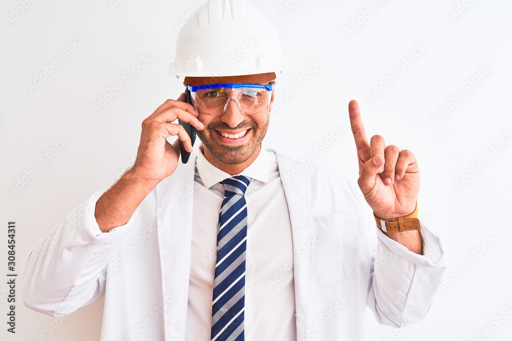 Young scientist man wearing safety helmet and calling using smartphone over isolated background surprised with an idea or question pointing finger with happy face, number one Young scientist man wearing safety helmet and calling using smartphone over isolated background surprised with an idea or question pointing finger with happy face, number one