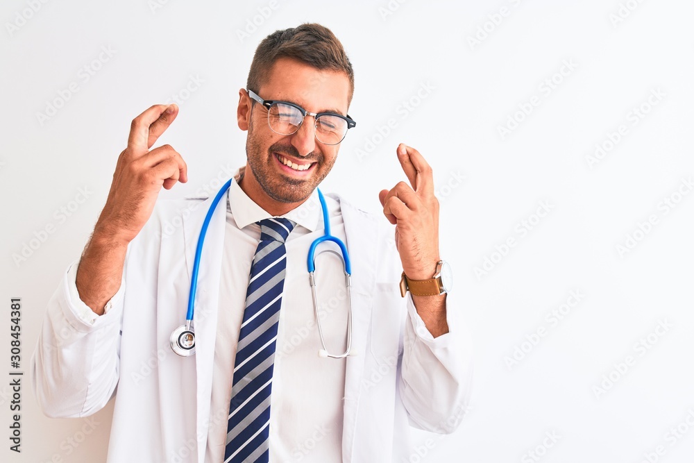 Young handsome doctor man wearing stethoscope over isolated background gesturing finger crossed smiling with hope and eyes closed. Luck and superstitious concept. Young handsome doctor man wearing stethoscope over isolated background gesturing finger crossed smiling with hope and eyes closed. Luck and superstitious concept.