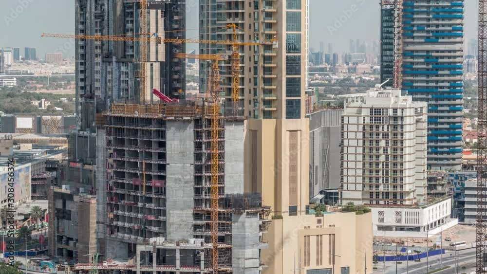 Aerial view of a skyscraper under construction with huge cranes in Dubai timelapse. Traffic on the road in downtown. United Arab Emirates Aerial view of a skyscraper under construction with huge cranes in Dubai timelapse. Traffic on the road in downtown. United Arab Emirates