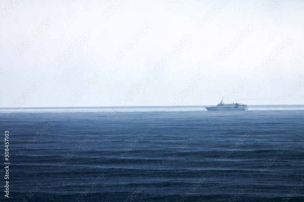 Ship sails by sea from right to left during rain