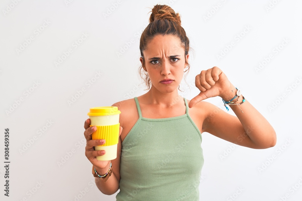 Young beautiful redhead woman drinking take away coffee over isolated background with angry face, negative sign showing dislike with thumbs down, rejection concept Young beautiful redhead woman drinking take away coffee over isolated background with angry face, negative sign showing dislike with thumbs down, rejection concept