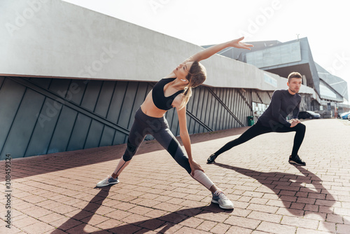 Beautiful fitness sportgirl and sportmen  with fit body in sportswear exercising outdoors, stretching, yoga, outdoor sports, urban style. photo