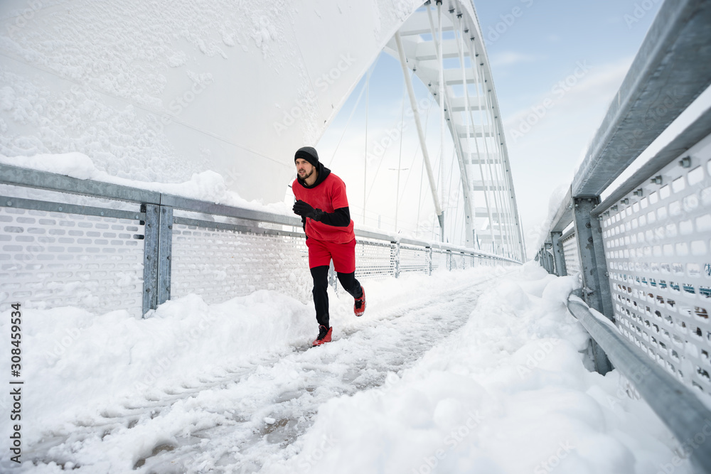 Sportive man running on a bridge in winter