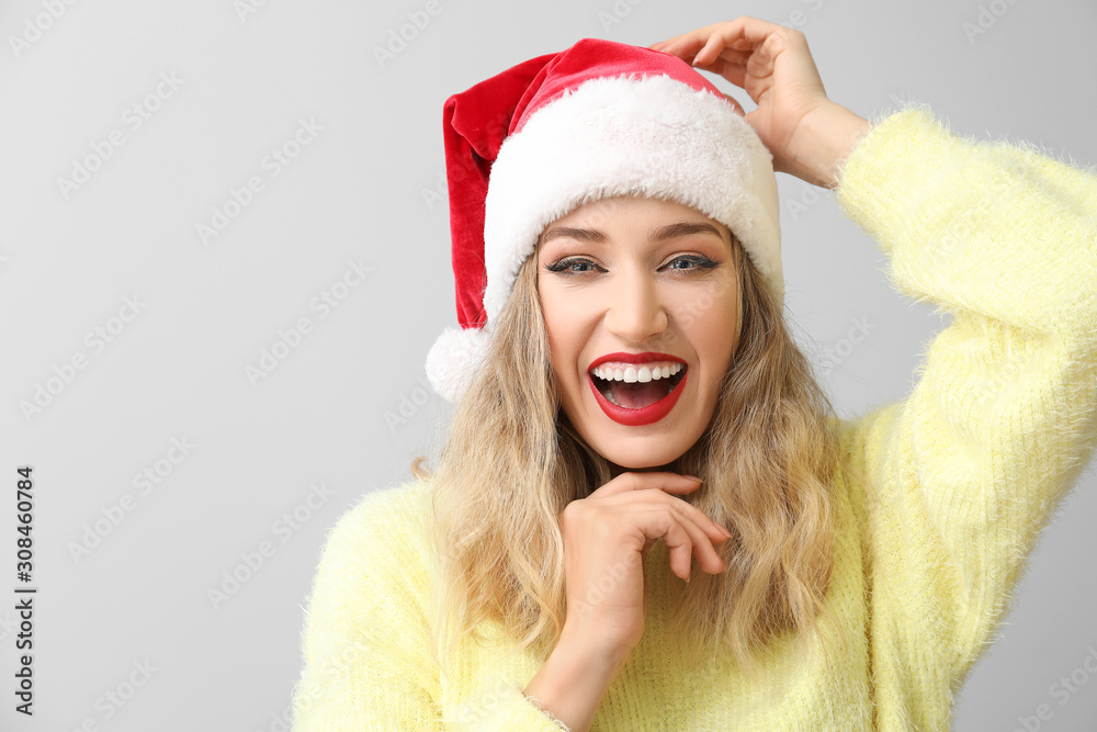 Beautiful young woman in Santa hat on light background Beautiful young woman in Santa hat on light background