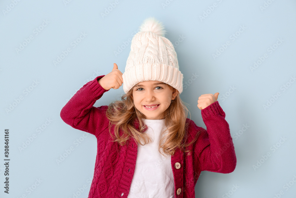 Cute girl in winter clothes showing thumb-up on color background Cute girl in winter clothes showing thumb-up on color background
