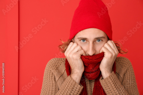 Handsome man in winter clothes on color background