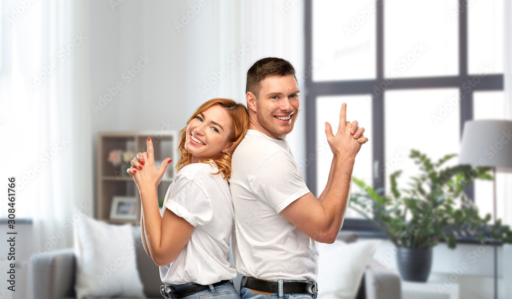 relationships and people concept - portrait of happy couple in white t-shirts making gun gesture over home background relationships and people concept - portrait of happy couple in white t-shirts making gun gesture over home background