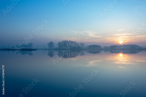 Sunset on a foggy lake and trees on the horizon