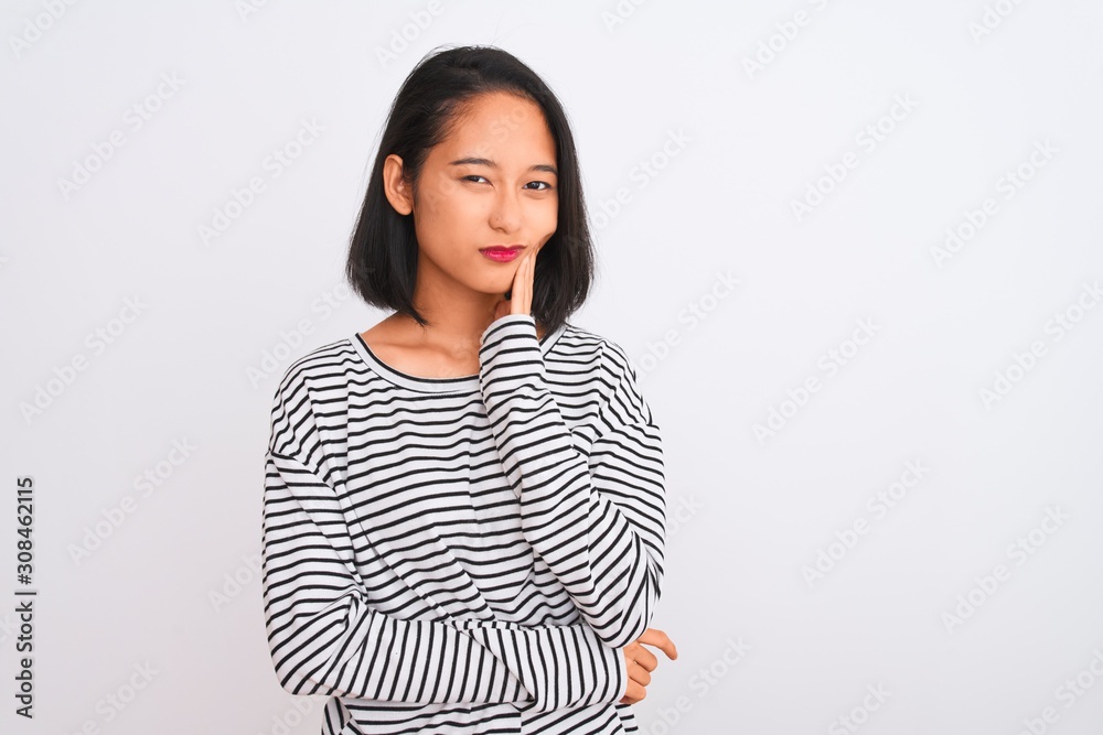 Young chinese woman wearing striped t-shirt standing over isolated white background touching mouth with hand with painful expression because of toothache or dental illness on teeth. Dentist concept. Young chinese woman wearing striped t-shirt standing over isolated white background touching mouth with hand with painful expression because of toothache or dental illness on teeth. Dentist concept.