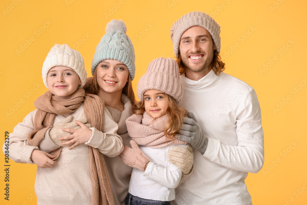 Happy family in winter clothes on color background
