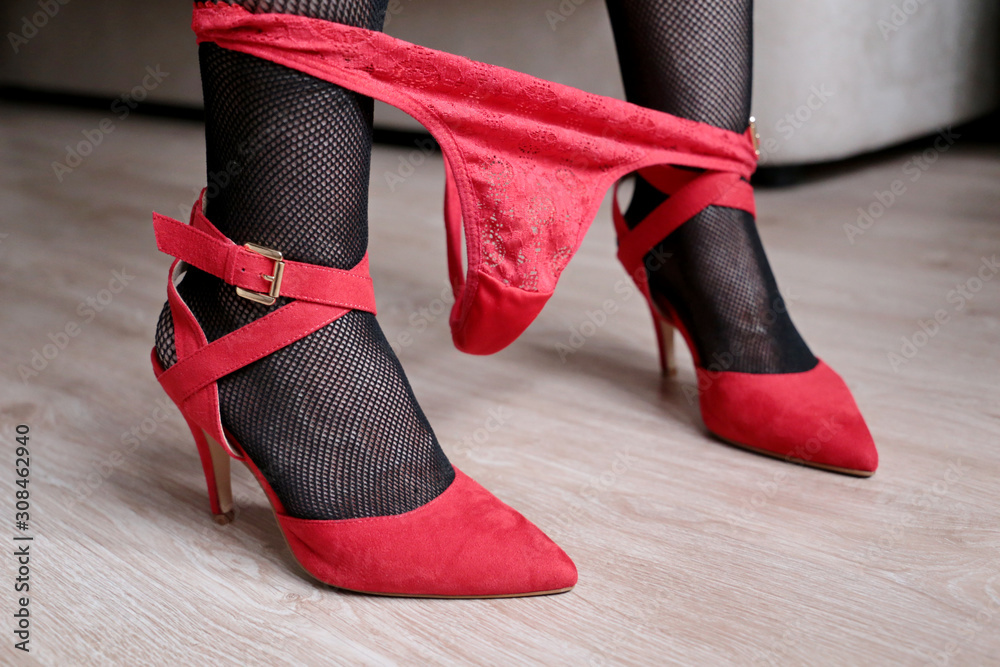 Woman wear high net socks and underwear sitting on the sofa holding with  her feet a red chili pepper Stock Photo