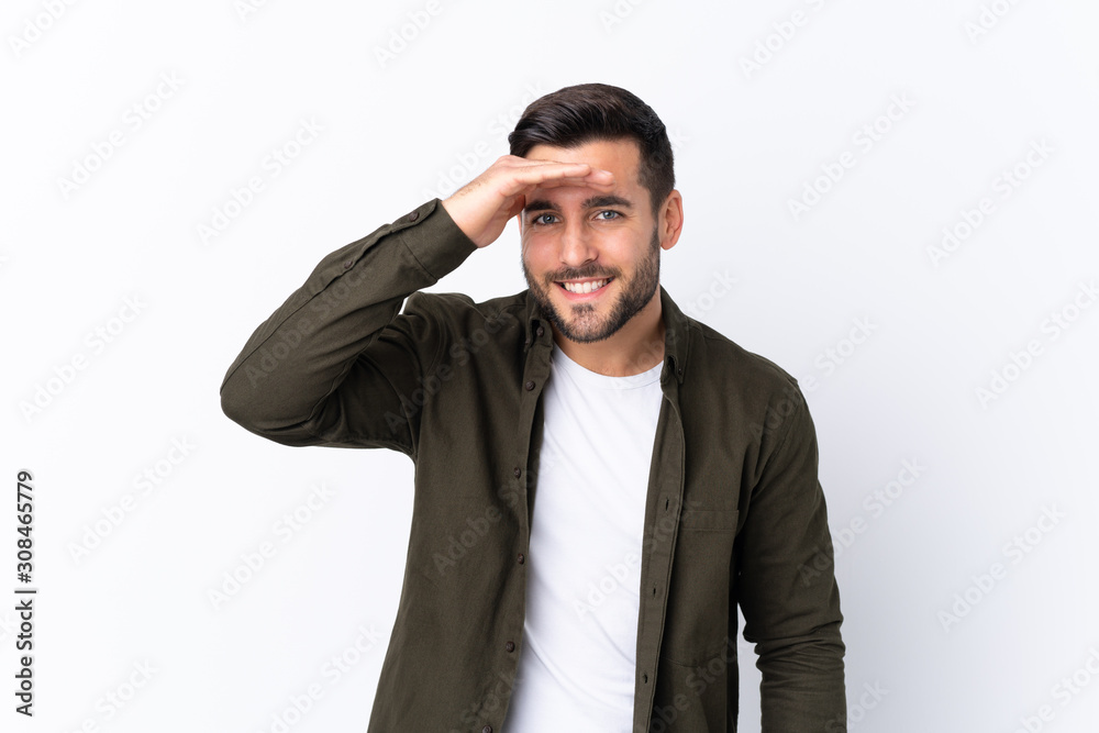 Young handsome man with beard over isolated white background looking far away with hand to look something Young handsome man with beard over isolated white background looking far away with hand to look something