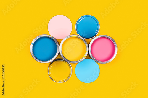 Renovation concept. Yellow background with three paint cans, colored circles and caps. Flat lay, top view, copy space.