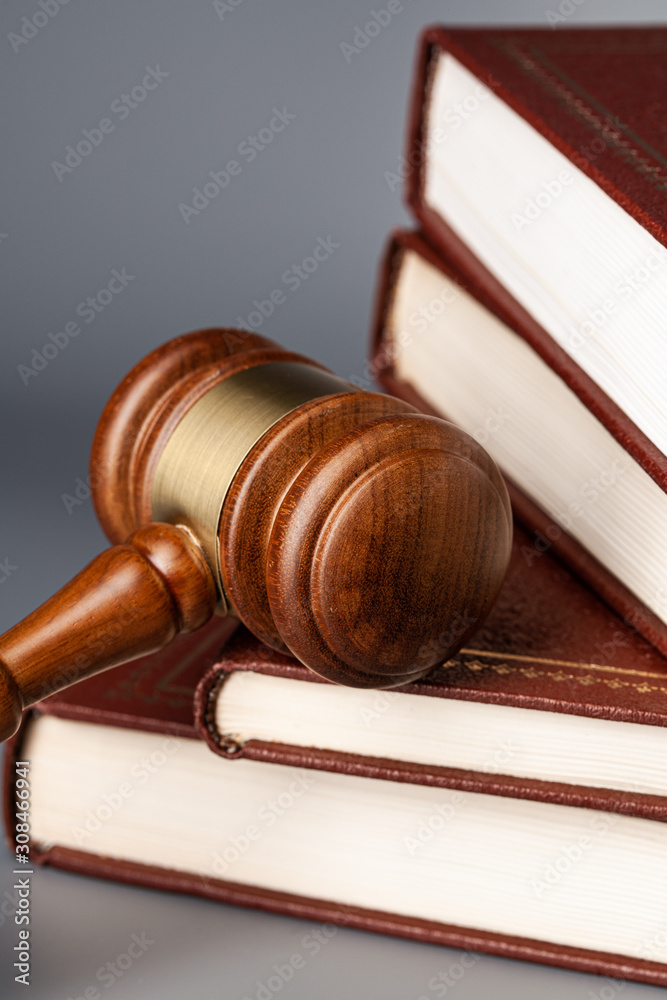 Brown wooden gavel with stack of books on gray table Brown wooden gavel with stack of books on gray table