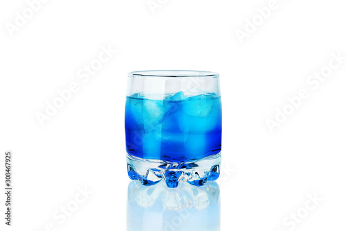 One glass of blue alcohol drink with ice cubes and reflection on white background isolated closeup, blue lagoon cocktail, absinthe shot, sambuсa, blue сuracao liquor, abstract neon color cold beverage