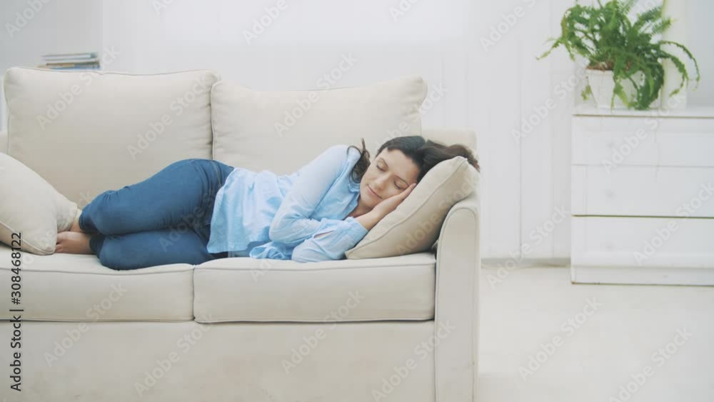 Slowmo. Satisfied brunette women sleeps on the sofa at home. Woman is dreaming pleasant dreams. 4K. Slowmo. Satisfied brunette women sleeps on the sofa at home. Woman is dreaming pleasant dreams. 4K.