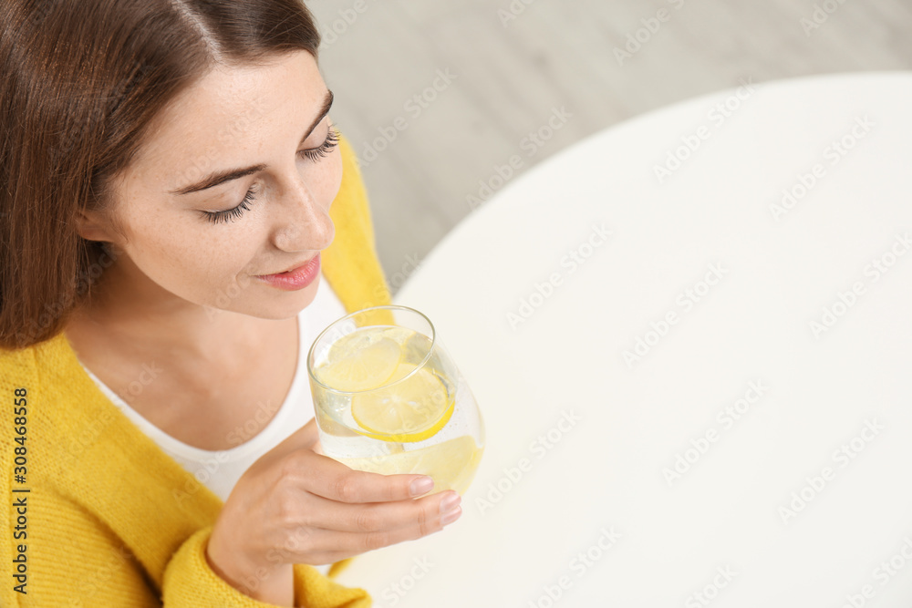 Young woman drinking lemon water at white table, above view. Space for text Young woman drinking lemon water at white table, above view. Space for text