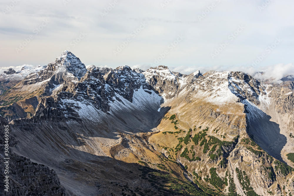 Fototapeta premium Alpine landscape above the tree line in late fall with partially snow-covered mountains. Hochvogel mountain in the background. Allgau Alps, Tirol, Austria