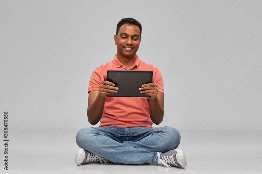 technology, internet, communication and people concept - happy indian man with tablet computer sitting on floor over grey background technology, internet, communication and people concept - happy indian man with tablet computer sitting on floor over grey background