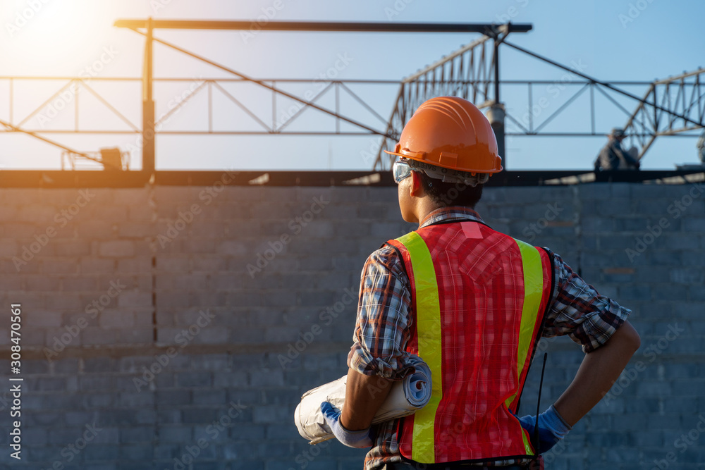 Backside Engineer Asia smart handsome and holding the digital blueprint in constructions site Backside Engineer Asia smart handsome and holding the digital blueprint in constructions site