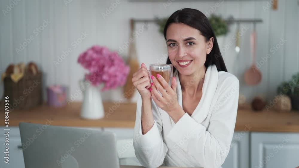 Young woman holding cup of tea in her hands, looking at camera and smiling Young woman holding cup of tea in her hands, looking at camera and smiling
